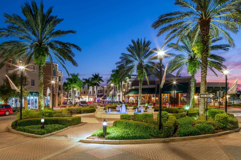 Fountain, palms and illuminated storefronts on Lakewood Ranch Main Street at dusk