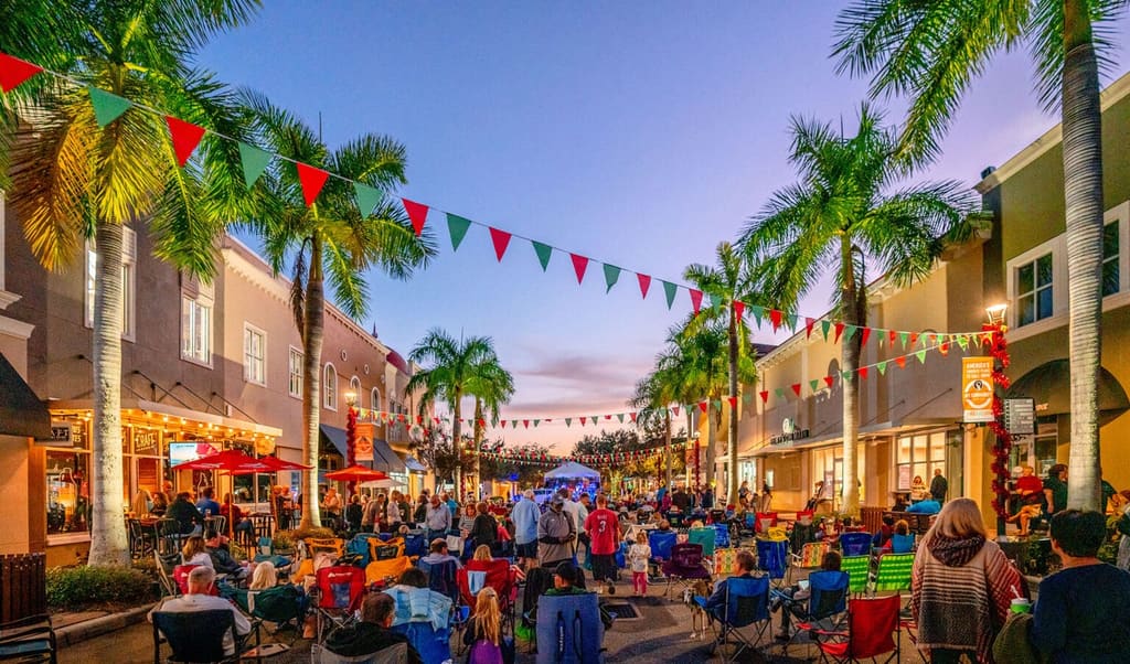 Concertgoers gather under palms and festive flags for Music on Main in Lakewood Ranch at dusk