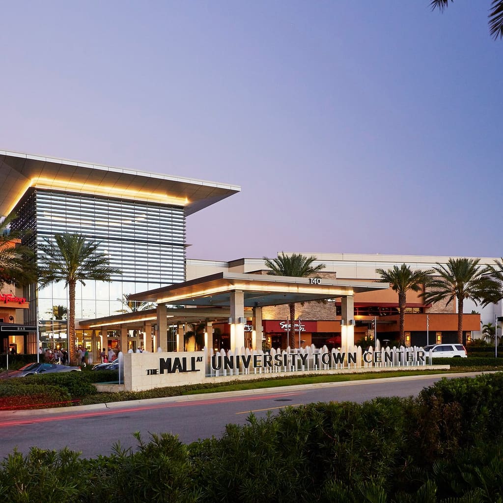 The illuminated west entrance and sign at The Mall at University Town Center at dusk